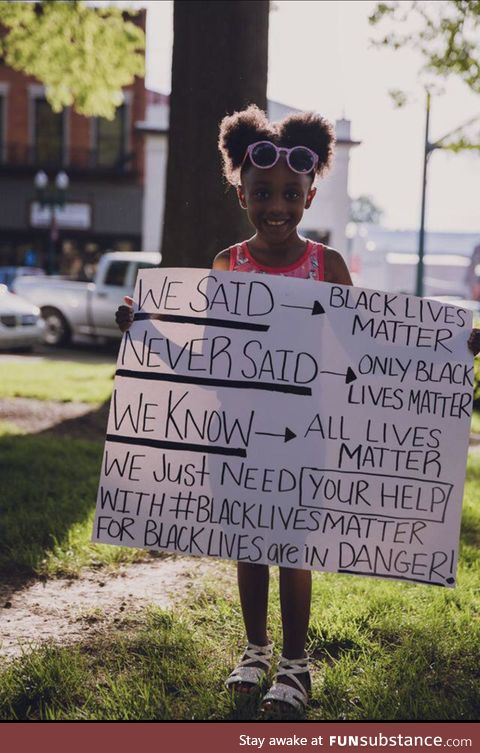 A young girl holding a sign to help explain Black Lives Matter to those who say All Lives