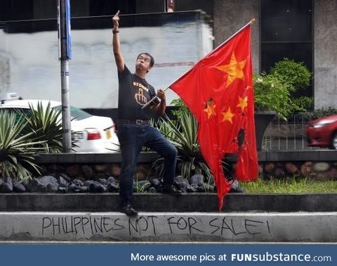 Filipino giving the finger to the Chinese embassy while burning their flag