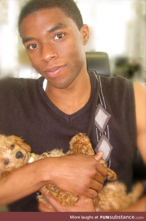 Young Chadwick Boseman holding a puppy