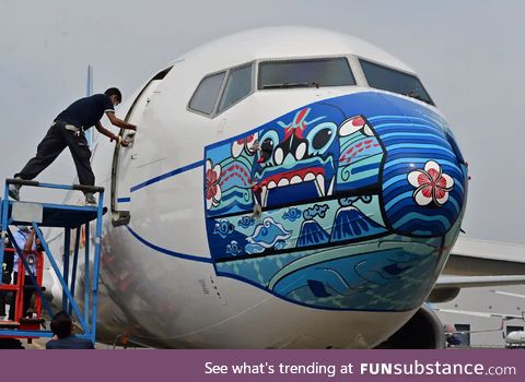 A worker outside a Garuda Indonesia Boeing with a new face mask design to promote COVID