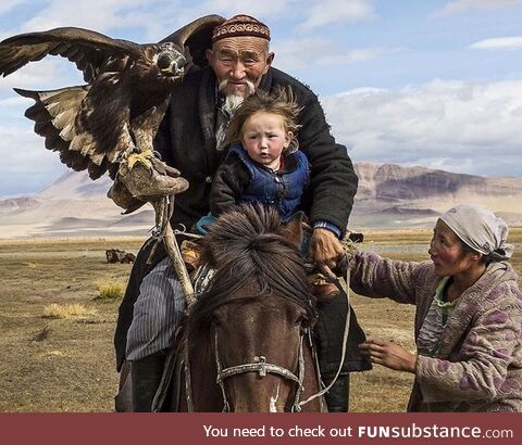 Man taking grandson and an eagle on hunt in the Altai Mountains of Central Asia