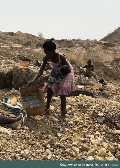 This teenager in DR Congo putting her baby into a cardbox, so she can dig cobalt used for