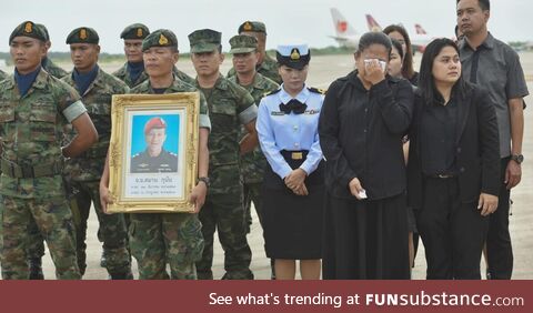 A guard holding a picture of Samarn Kunan, 38, a diver who died saving 13 lives in a