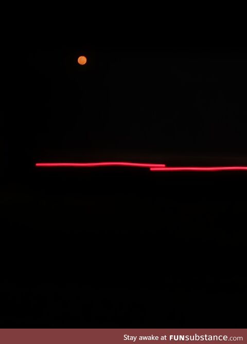 Orange-ish moon above a moving truck's light making it look like it was a drawing