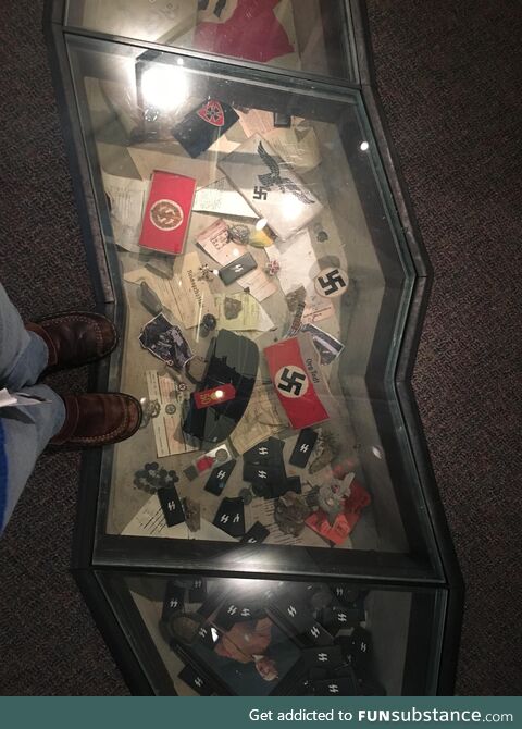 A case of Nazi paraphernalia set in the floor of a Holocaust museum, forcing visitors to