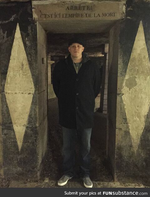 Me standing at the entrance to the Paris Catacombs. It says “Stop! This is the Empire