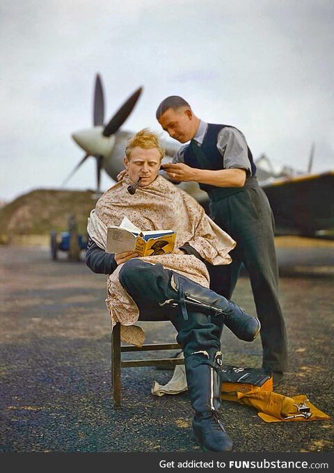 An RAF pilot getting a haircut during a break with a Spitfire in the background (1942)