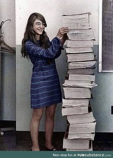 Margaret Hamilton standing by the code that she wrote by hand to take humanity to the