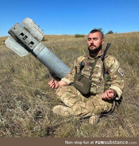 Ukrainian soldier meditating beside a missile