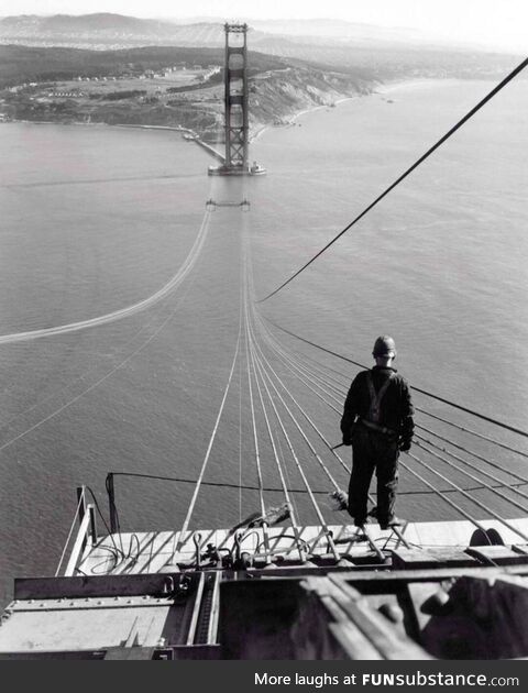 A man poses on the first cables during construction of the Golden Gate Bridge, 1935