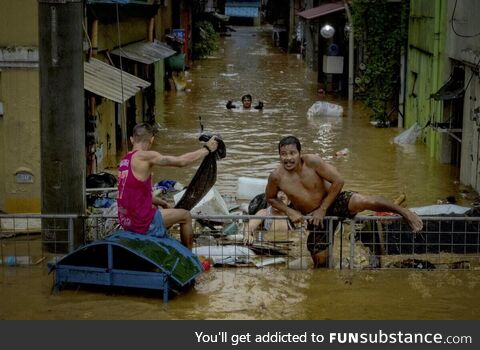 Residents of Manila climbing a fence to escape the flood caused by Typhoon Gaemi