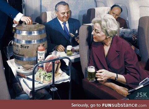 A Lufthansa flight attendant serves beer from a keg and ham during a flight in the 1960s