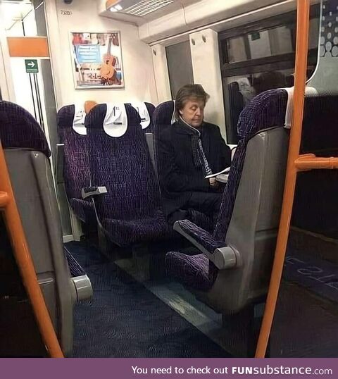 A man sitting on a train from London to Liverpool. His name is Sir Paul McCartney