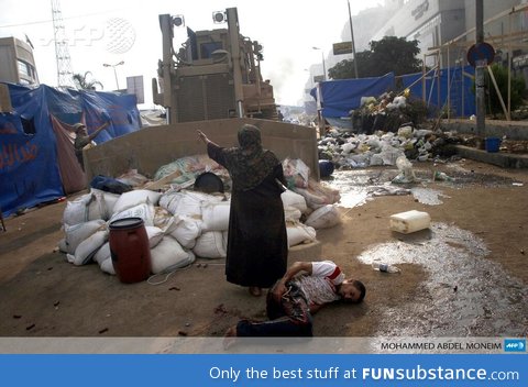 An Egyptian woman stands in front of bulldozer to protect an injured young man